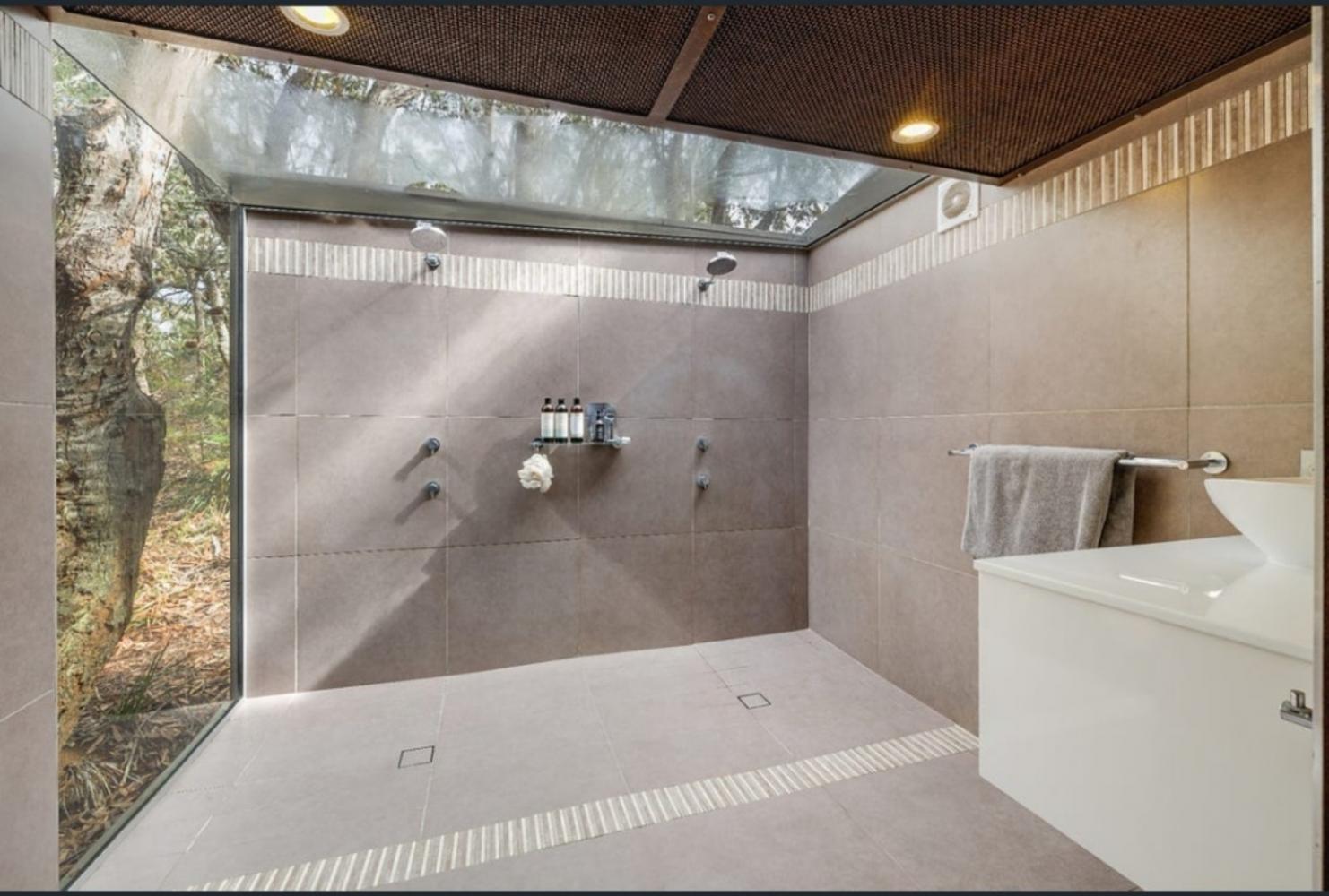 master bedroom ensuite with shower toilet and vanity. glass wall and roof to view the surrounding forest