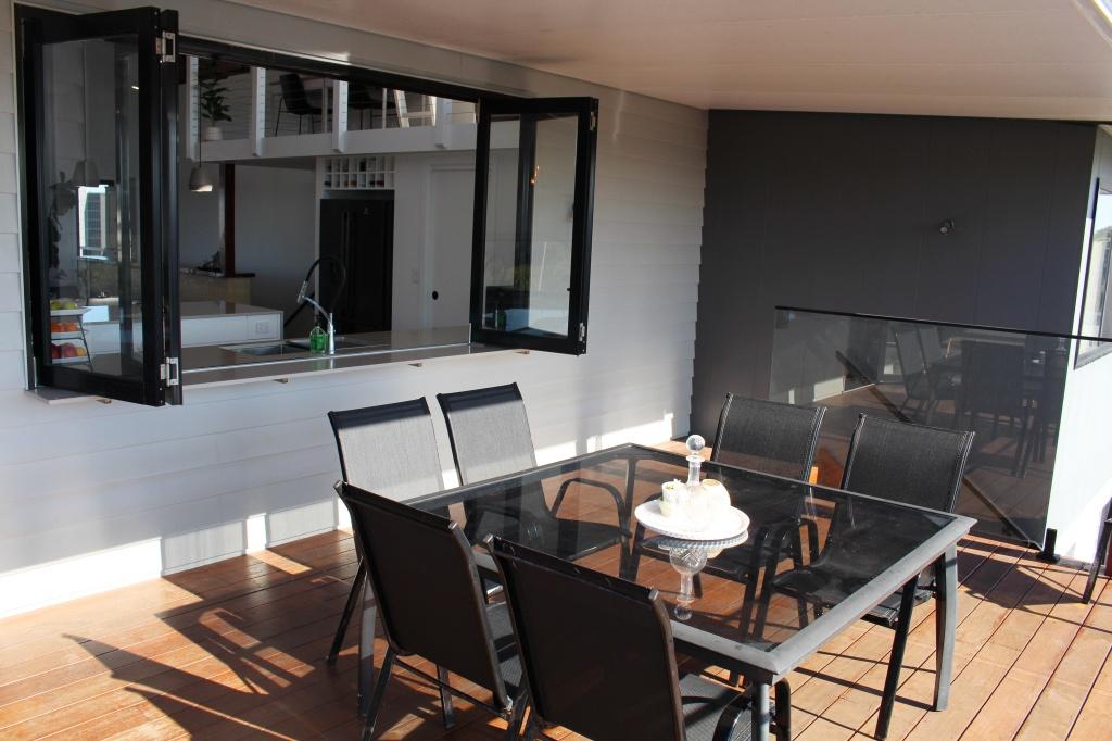 Large deck overlooking heated pool with four seater table with kitchen pass at Waterside Escape