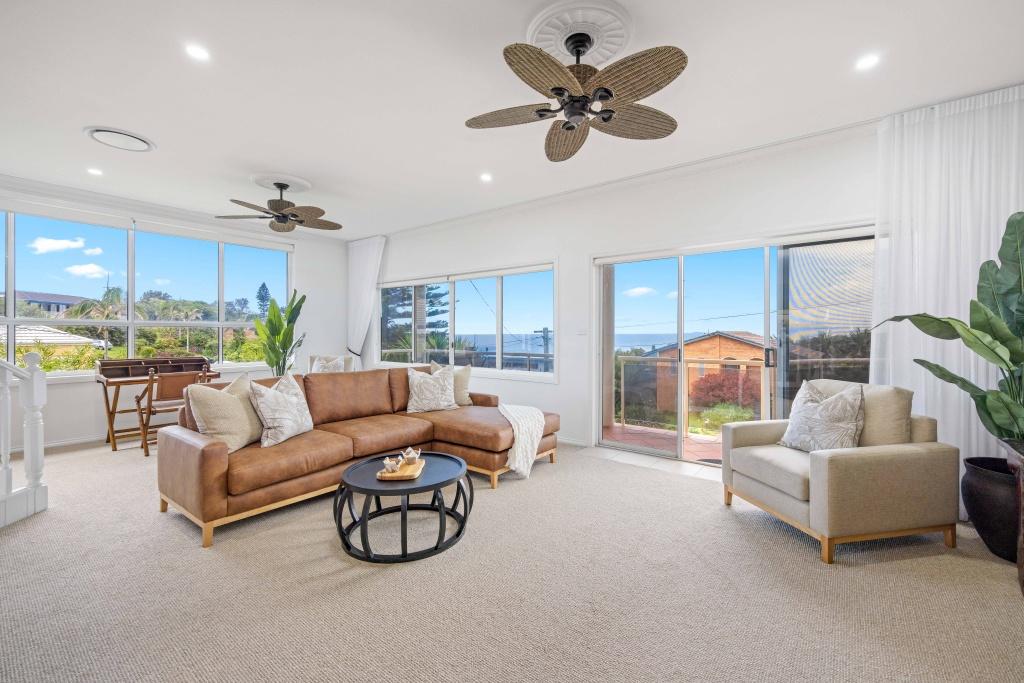 Lounge room with ceiling fan water views couch and arm chair at Beached at Lighthouse Port Macquarie